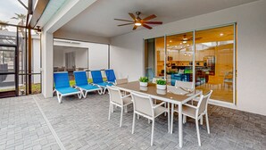 A patio area with a table and chairs, a ceiling fan, and a glass door leading to an interior space. - Spacious Private Home w/ Private Pool, Resort Style Waterpark & Mini Golf Access (Davenport)