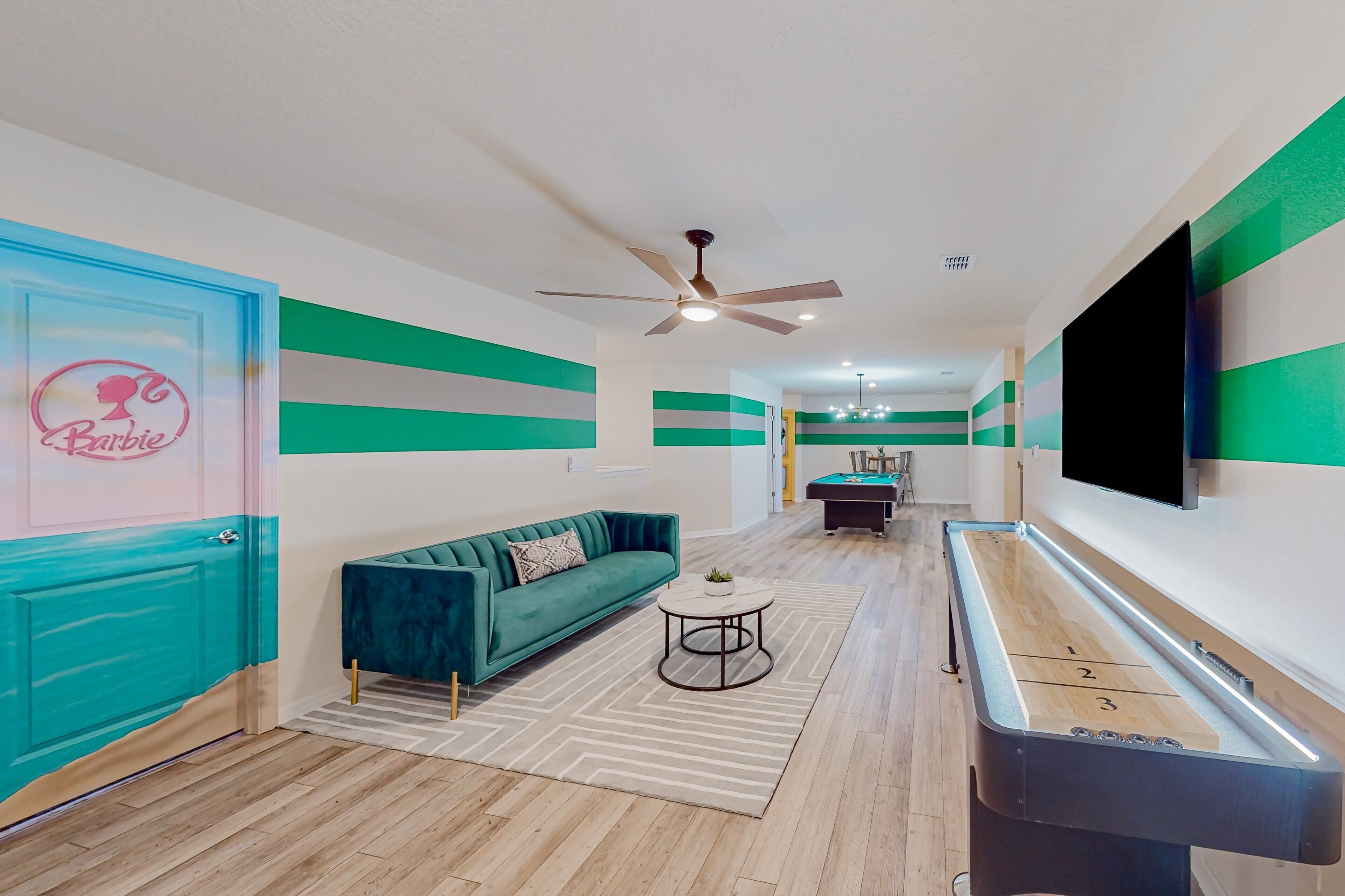 Una habitación con un sofá color turquesa, una mesa de billar y un ventilador de techo.