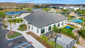 A building with a paved parking area, a basketball court, and a swimming pool. - Updated Townhome With an Enclosed Pool, Five Bedrooms, W/D - Close to Everything (Kissimmee)