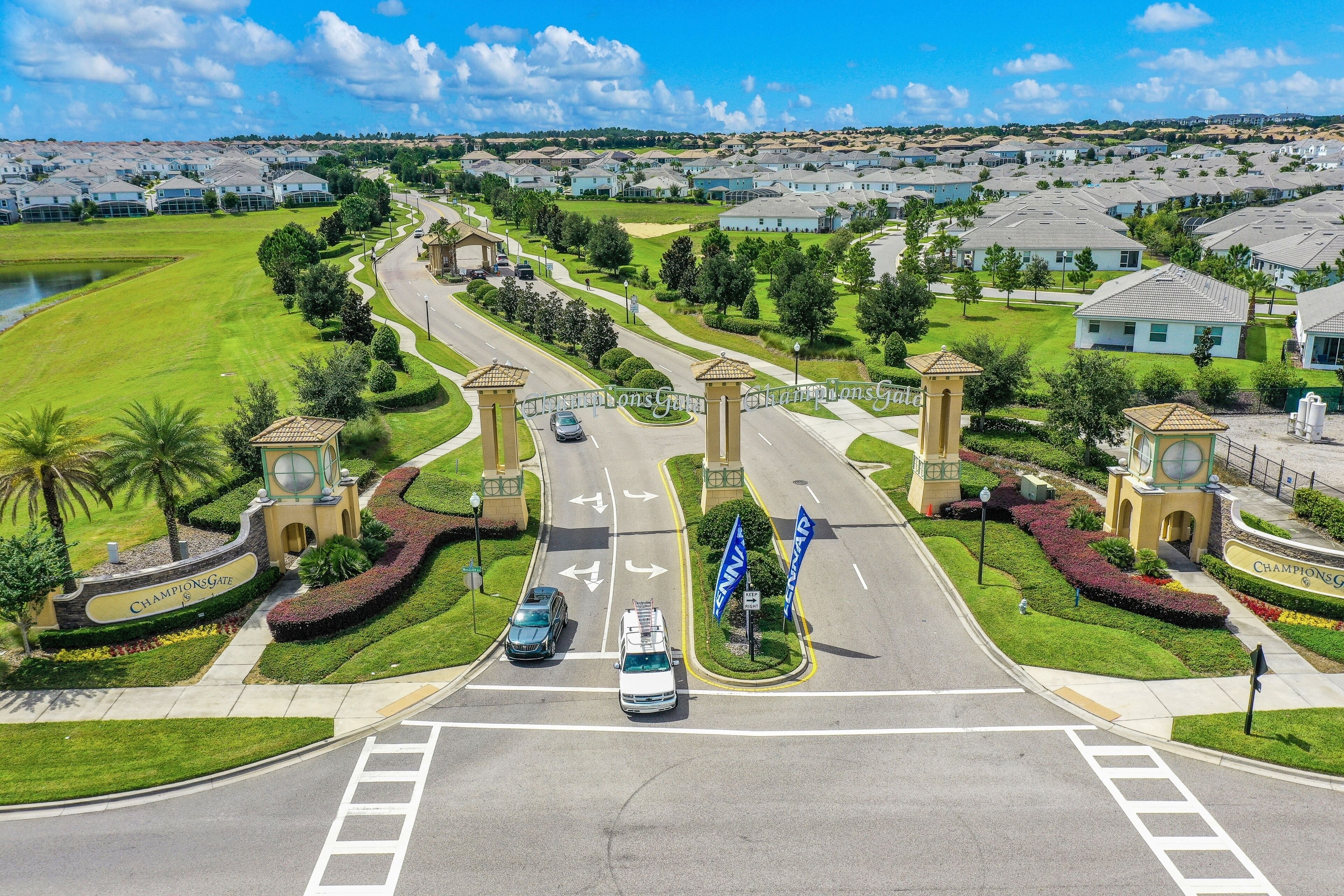 A residential area with a gated entrance, a road with directional arrows, and a large building with a clock tower.