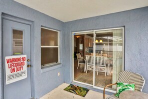 A residential entry with a warning sign, a sliding glass door, and a dining area visible through the door. - Snowbird-friendly Home Near Disney W/private Heated Pool, Lanai, Shared Tennis (Kissimmee)