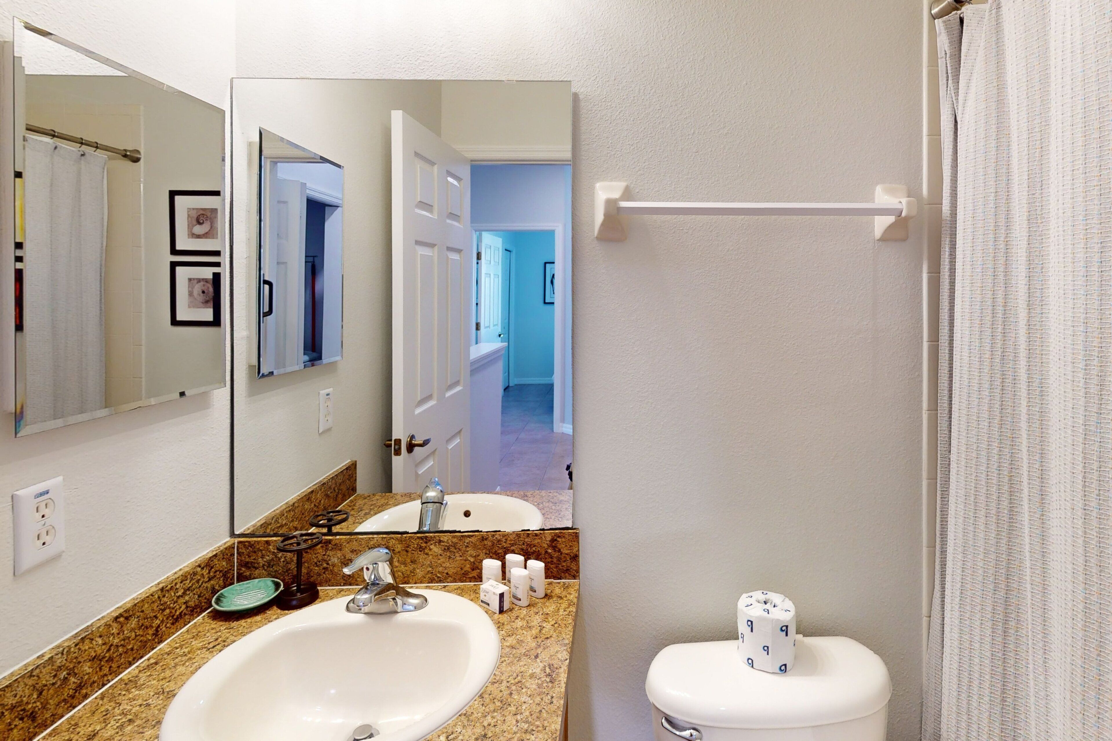 A bathroom with a sink, mirror, toilet, and towel rack.