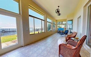 A spacious room with large windows, wicker furniture, and a ceiling fan. - Lakefront Home With Private Dock, Garage Parking, Sunroom,w/d & Wifi (Sebring)