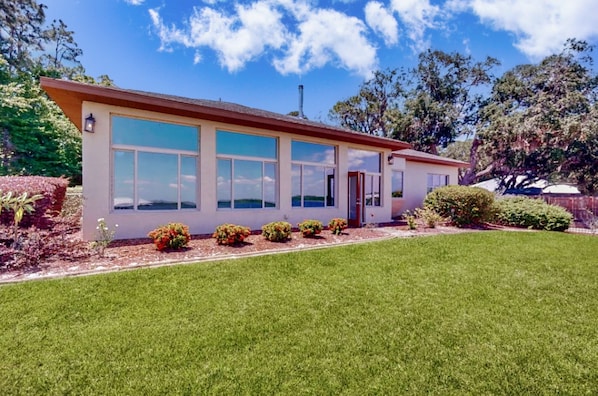 A single-story building with a flat roof, large windows, and a well-maintained lawn. - Lakefront Home With Private Dock, Garage Parking, Sunroom,w/d & Wifi (Sebring)