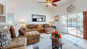 A living room with a ceiling fan, a large mirror, and a view of a swimming pool through glass doors. - Dog-friendly Getaway With Private Pool, Tennis & AC - Near Theme Parks (Davenport)
