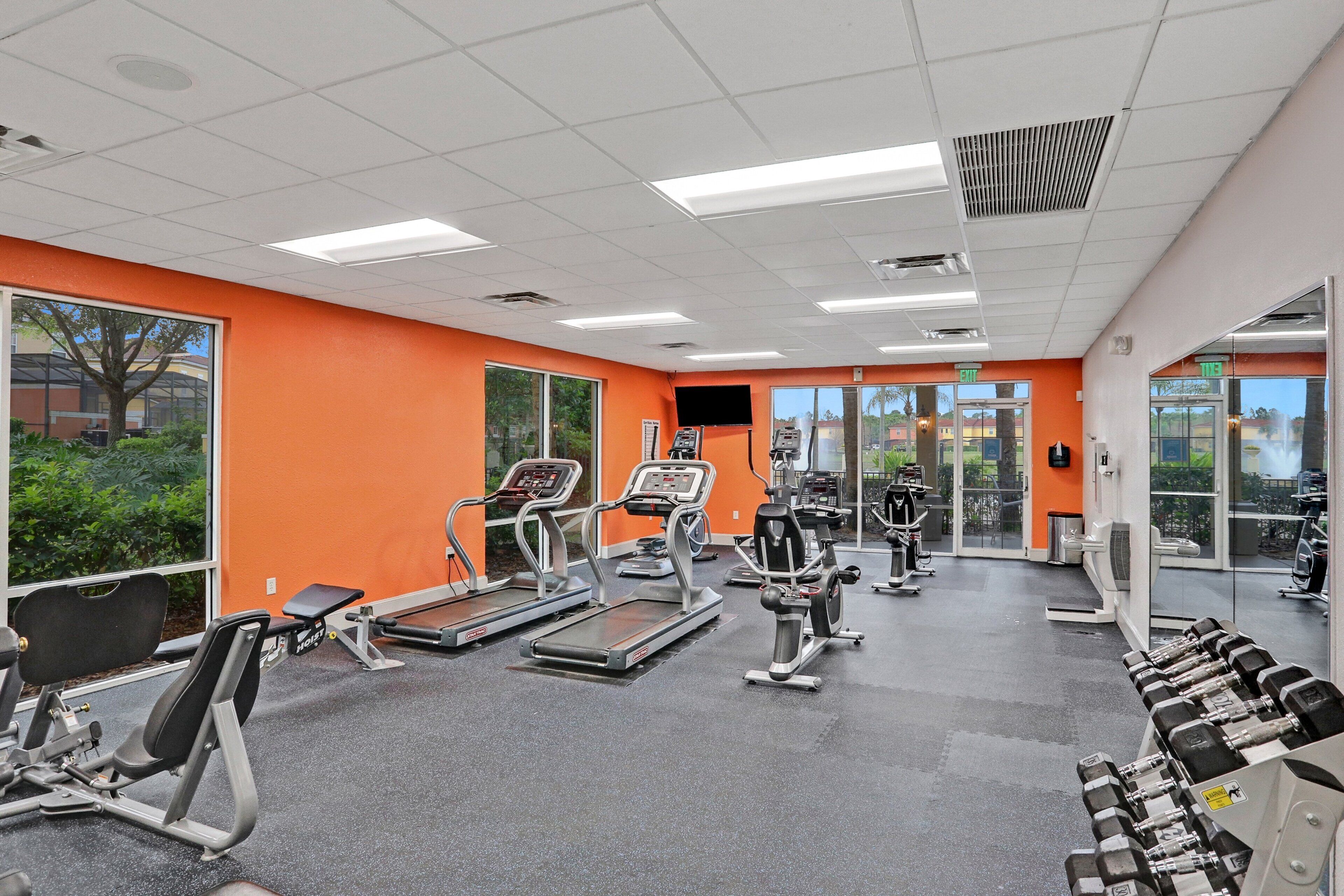 Ein Fitnessstudio mit Laufbändern, Crosstrainern und Gewichtsbänken.