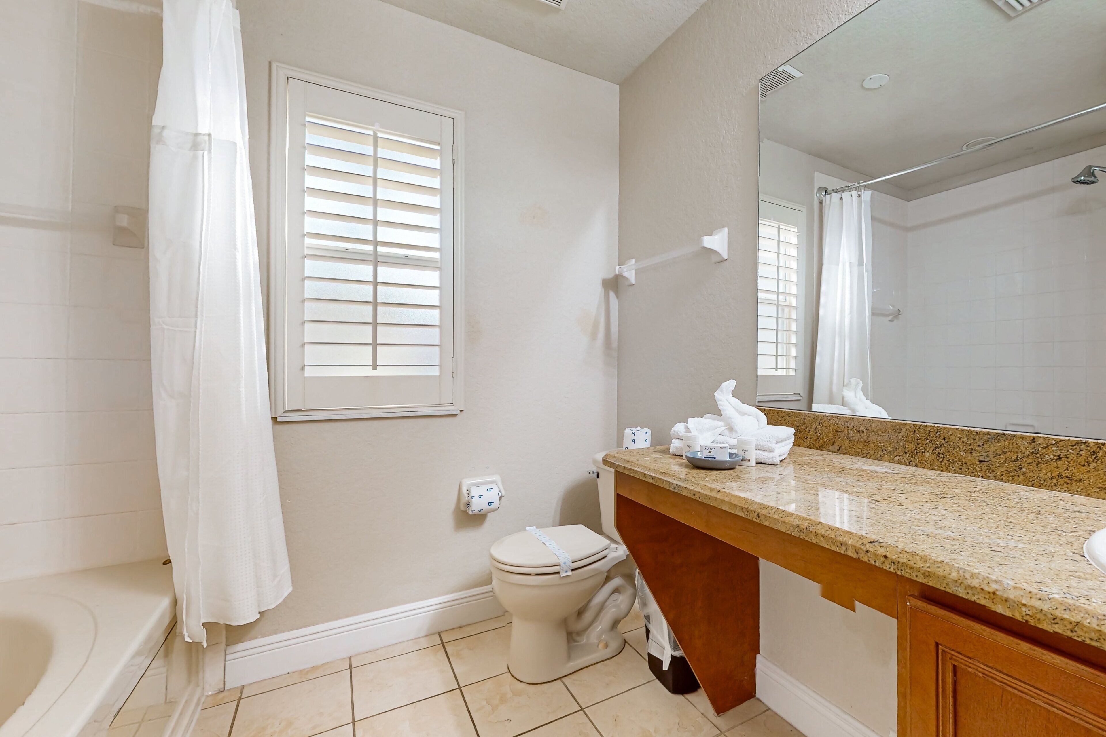 A bathroom with a toilet, shower, and vanity with a mirror.