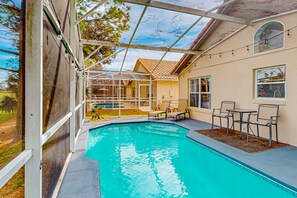 A swimming pool with a covered patio area, outdoor seating, and a view of the house. - Radiant Retreat With Private Pool, On-site Golf, Board Games, AC, & W/D (Haines City)