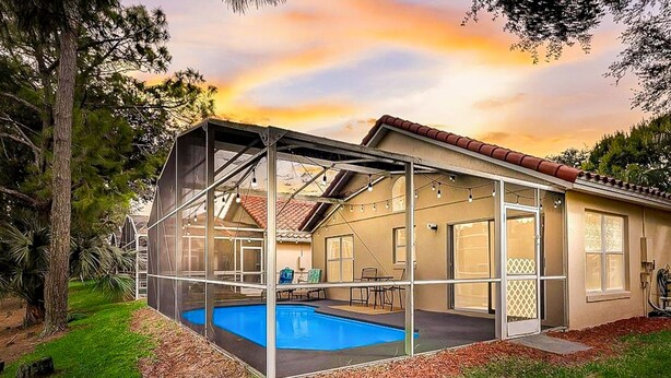 A house with a covered swimming pool, a patio, and a view of the sunset. - Radiant Retreat With Private Pool, On-site Golf, Board Games, AC, & W/D (Haines City)