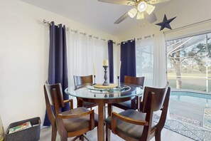 A round glass table with six wooden chairs, a ceiling fan, and a star decoration on the wall. - Radiant Retreat With Private Pool, On-site Golf, Board Games, AC, & W/D (Haines City)