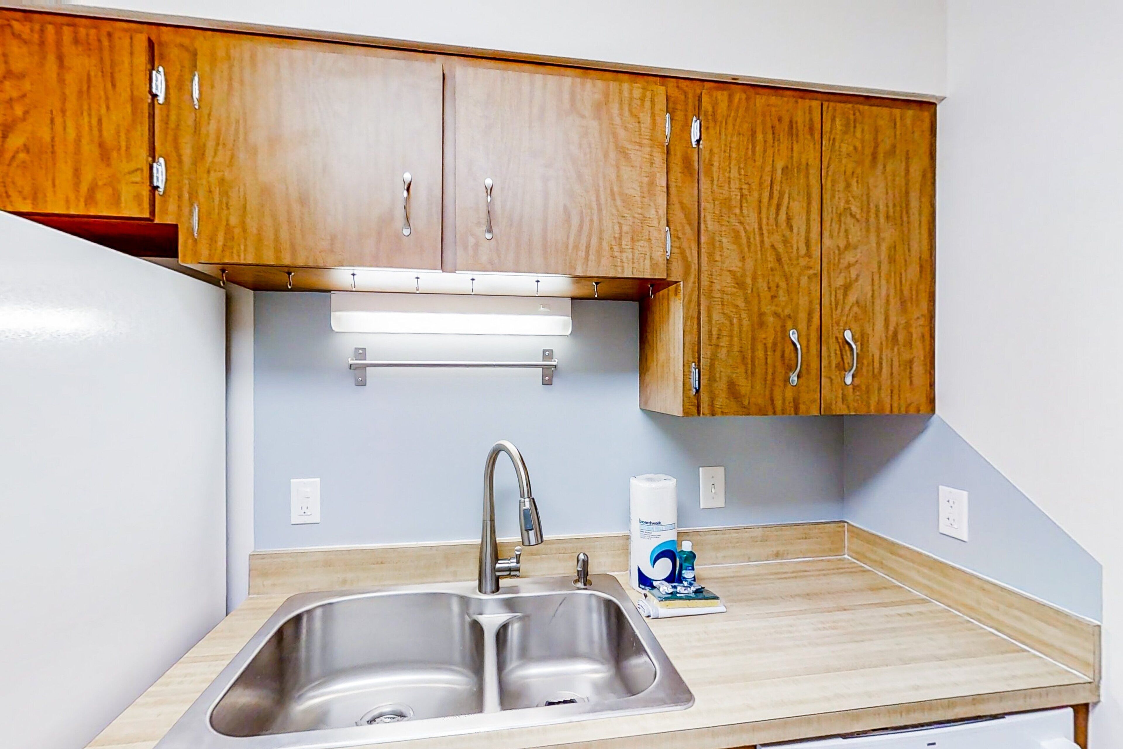 A kitchen with wooden cabinets, a stainless steel sink, and a countertop.