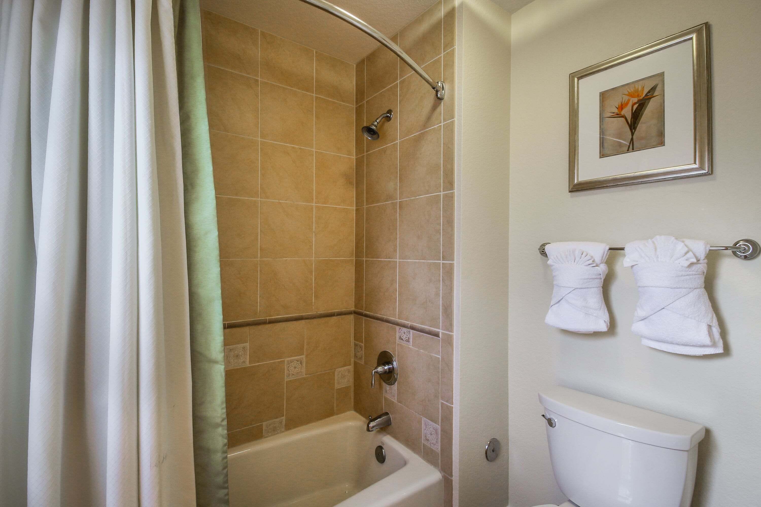 A bathroom with a bathtub, shower, toilet, and towels.