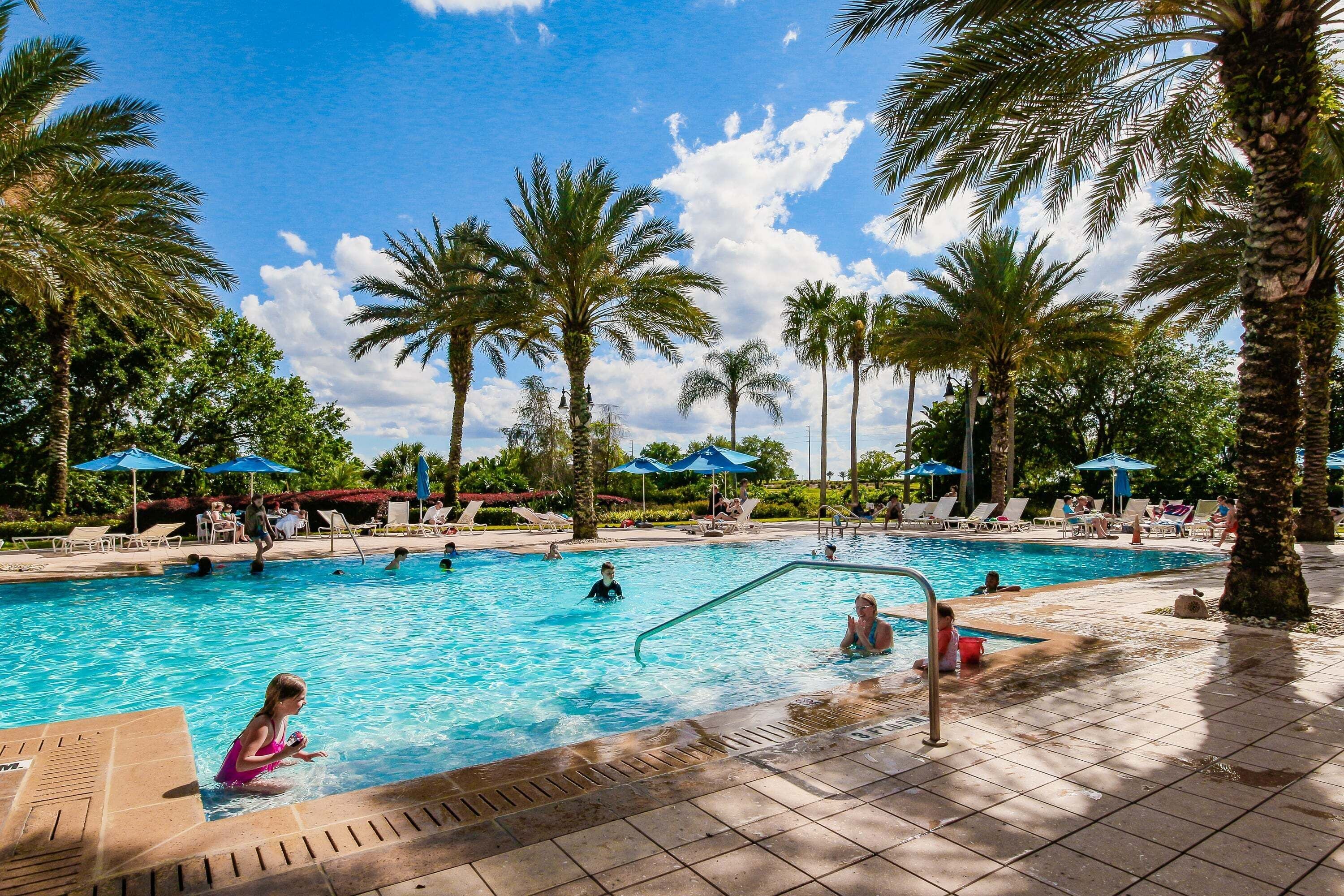 Ein Swimmingpool mit Palmen, Liegestühlen und Sonnenschirmen.
