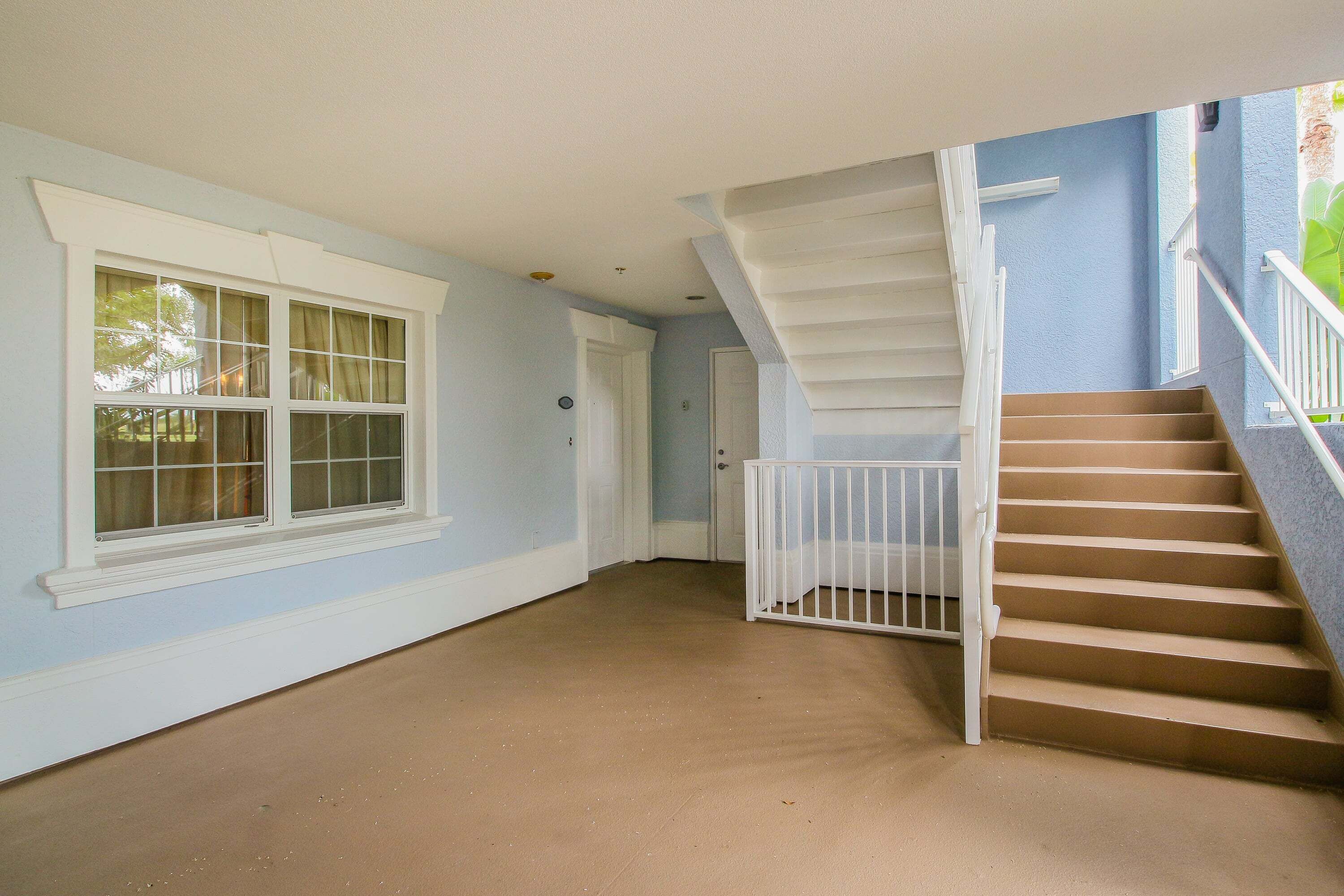 A hallway with a staircase, a door, and a window.