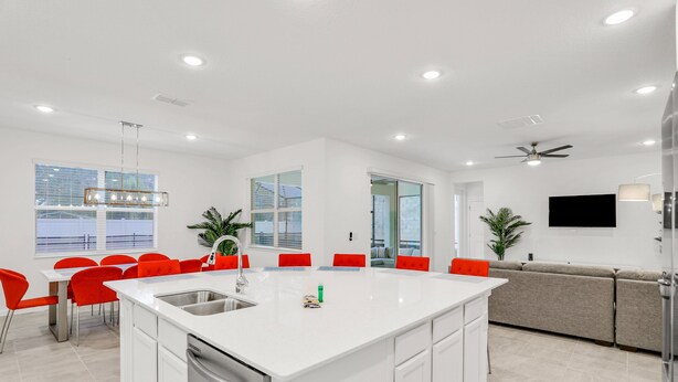 A modern kitchen with a central island, white cabinetry, and red chairs. - Dog-friendly Home With a Heated Pool, Pool Spa, In-home Theater, Lanai, & Patio (Kissimmee)