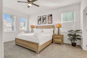 A bedroom with a bed, bedside tables, a ceiling fan, a potted plant, and artwork on the wall. - Dog-friendly Home With a Heated Pool, Pool Spa, In-home Theater, Lanai, & Patio (Kissimmee)