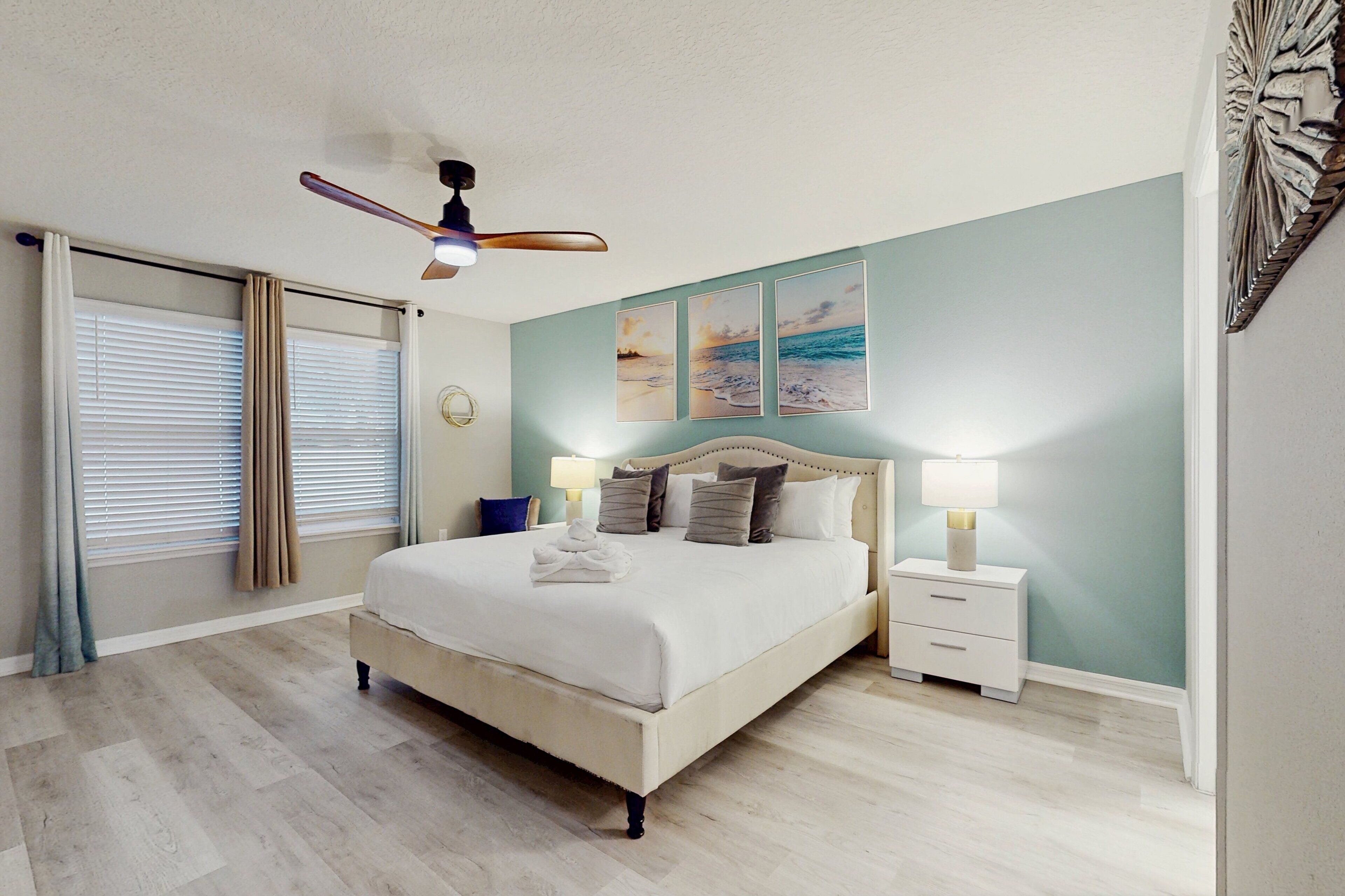 Ein Schlafzimmer mit einem Bett, Nachttischen, einem Deckenventilator und Bildern an der Wand.