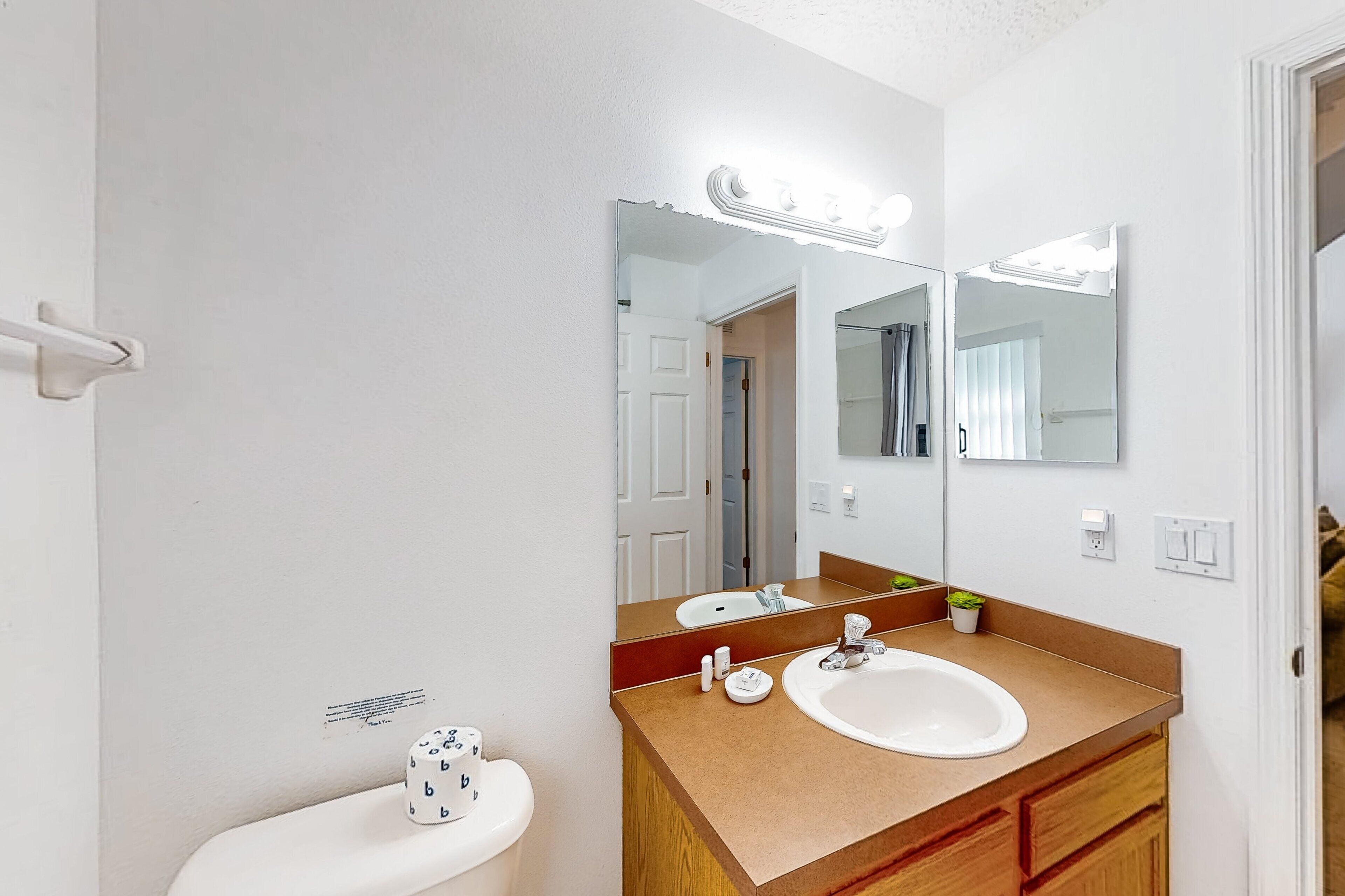 Un baño con un lavamanos blanco, un espejo y un inodoro.