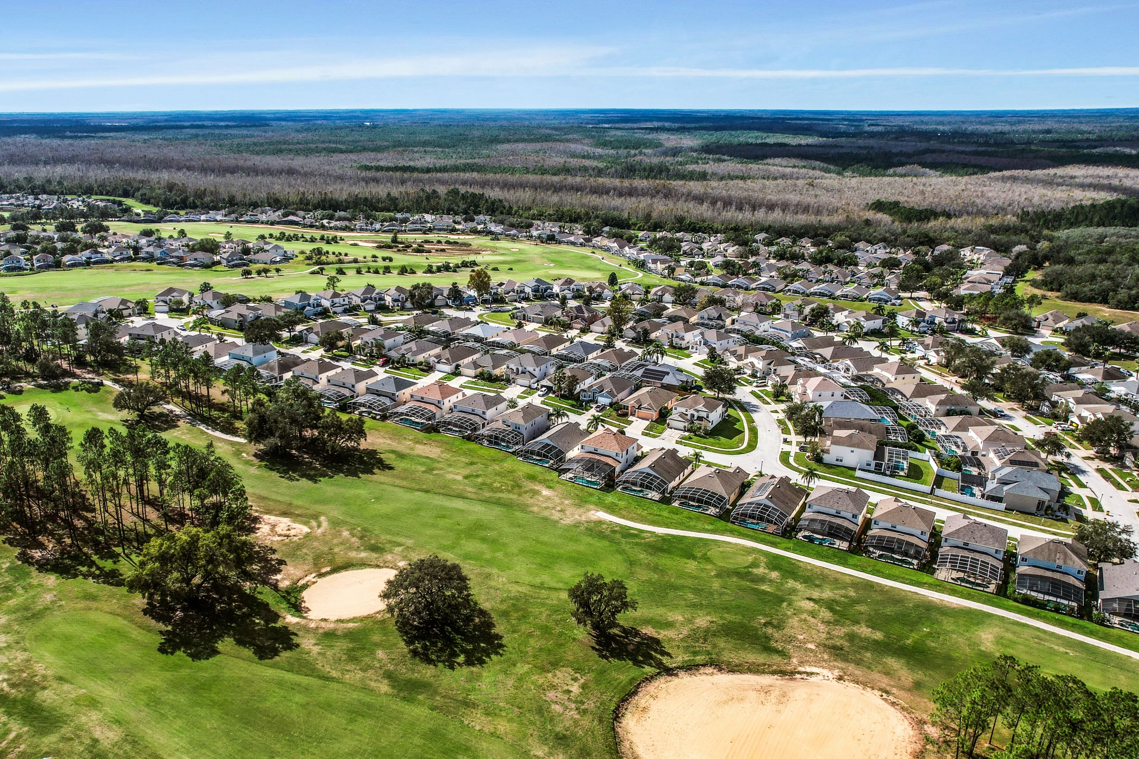Vue aérienne d’un quartier résidentiel avec des maisons, des espaces verts et un terrain de golf.