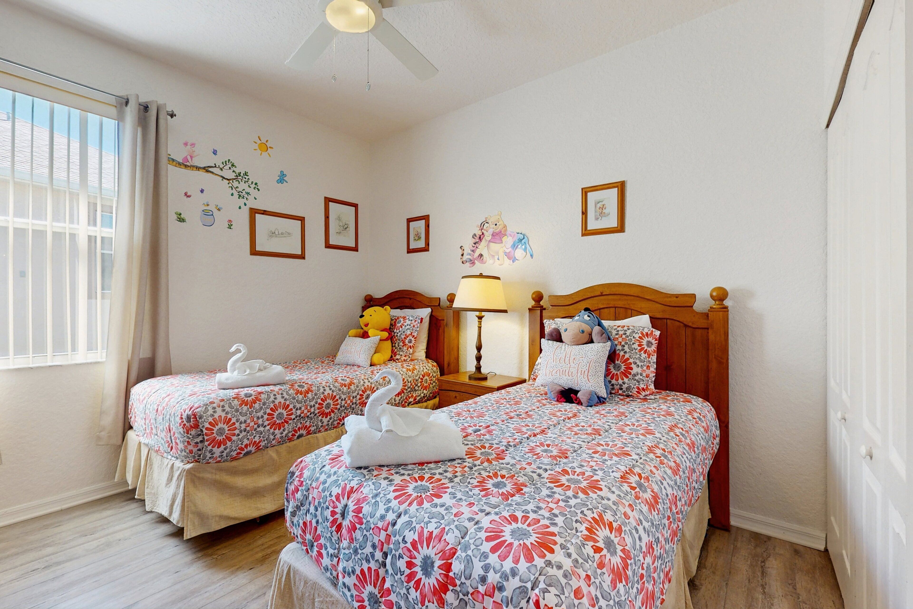 A hotel room with two beds, a ceiling fan, and decorative wall stickers.