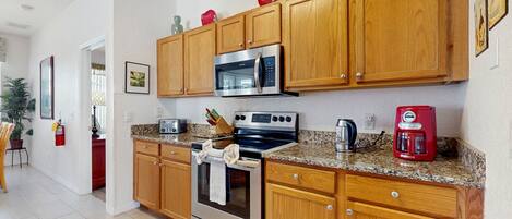 A modern kitchen with wooden cabinets, stainless steel appliances, and granite countertops.