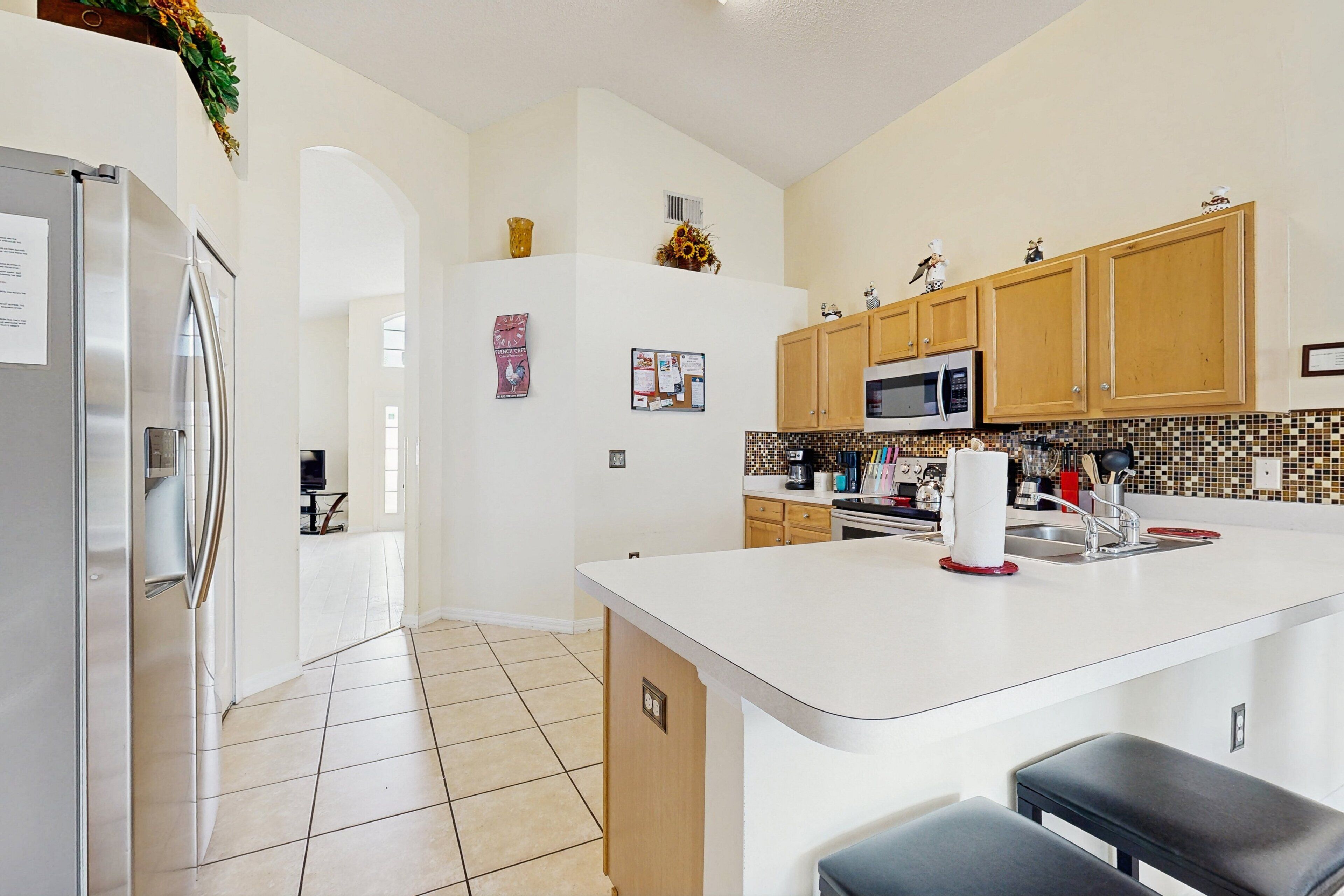 A modern kitchen with a central island, stainless steel appliances, wooden cabinets, and a tiled backsplash.
