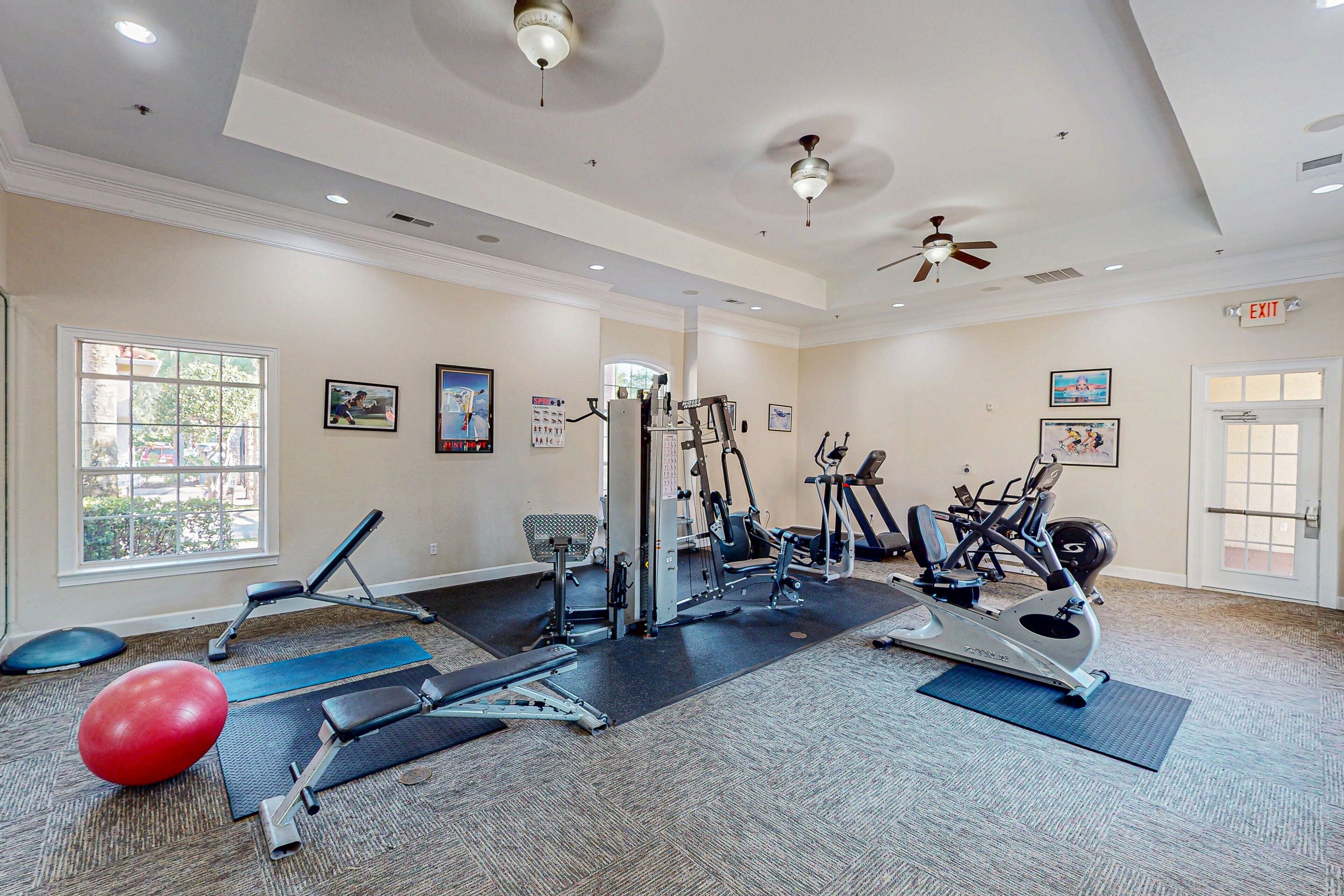A gym with exercise equipment, mats, and a red exercise ball.