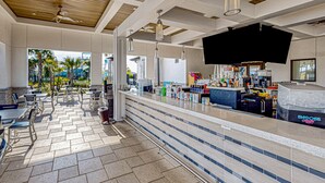 Un área de bar al aire libre con mostrador, asientos y vistas del exterior.