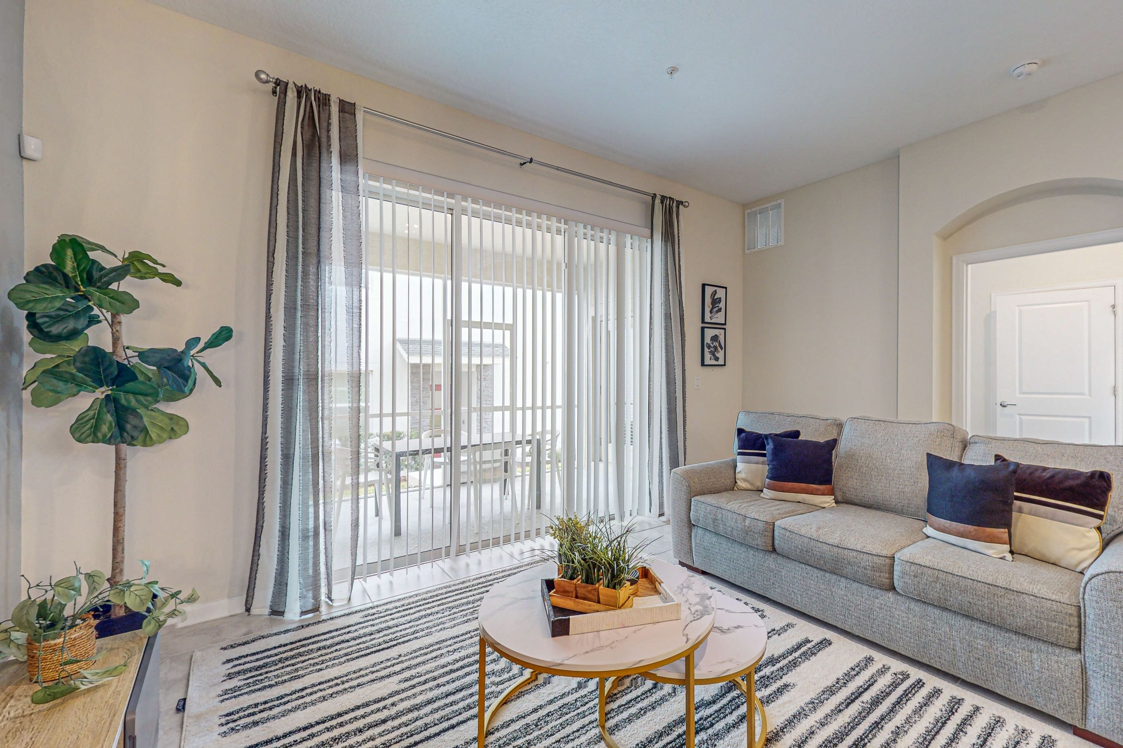 A modern living room with a grey sofa, a round coffee table, and a large window with curtains.