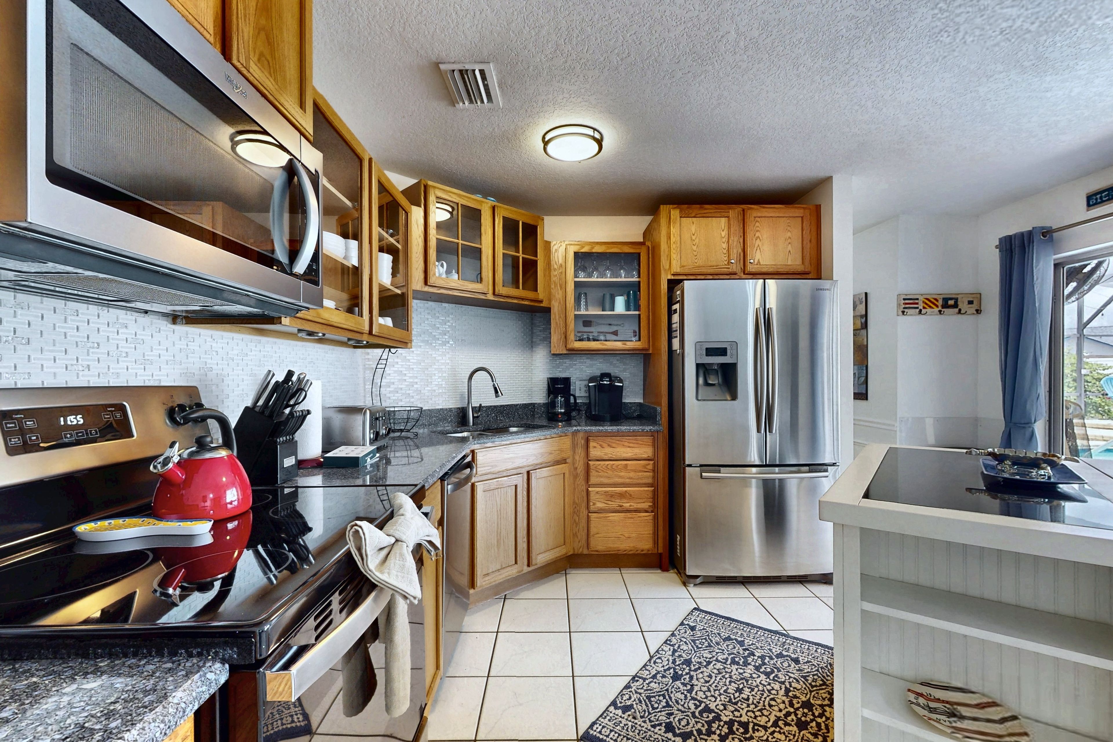A modern kitchen with stainless steel appliances, wooden cabinets, and a tiled backsplash.
