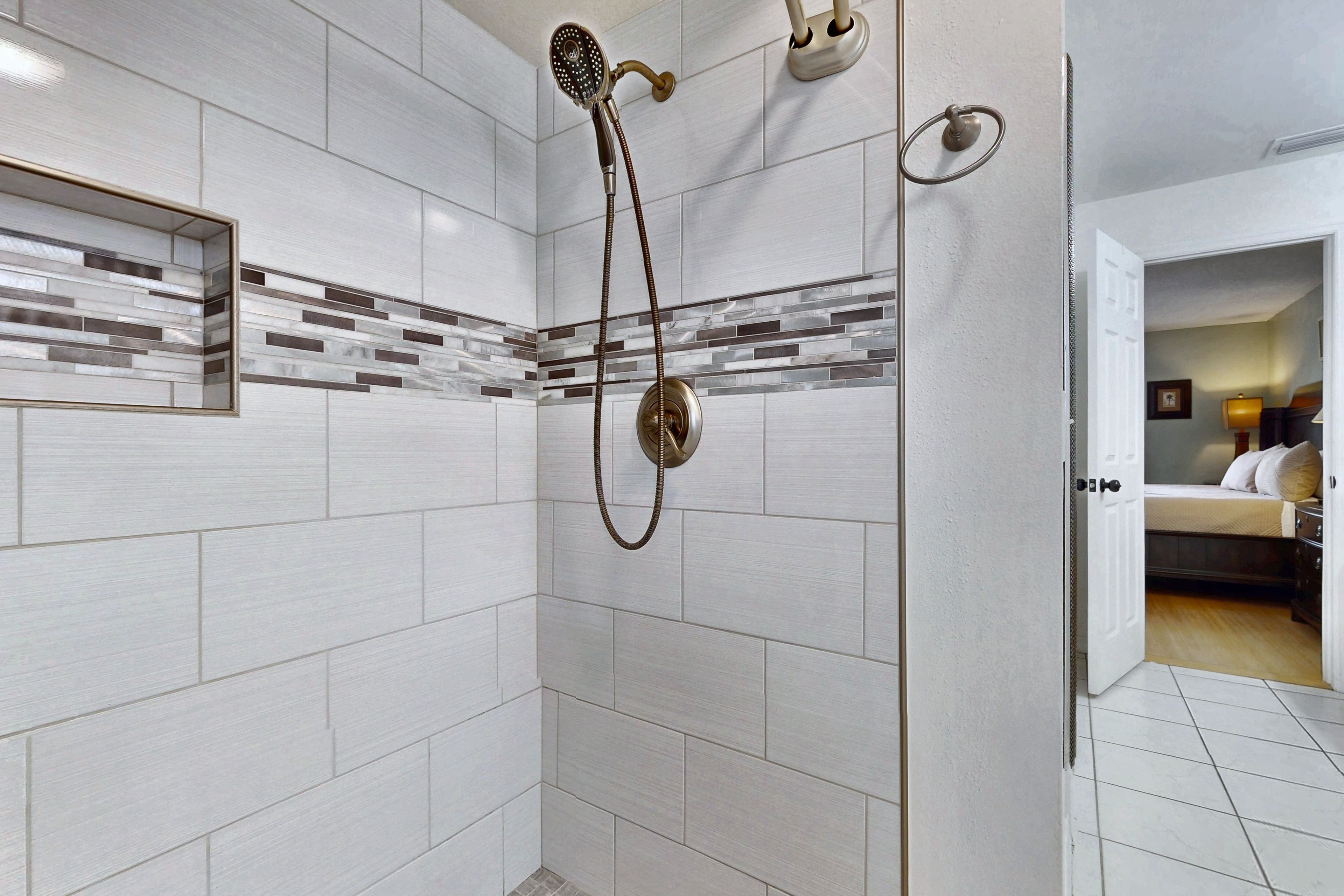 A shower with a handheld showerhead and a wall-mounted faucet.