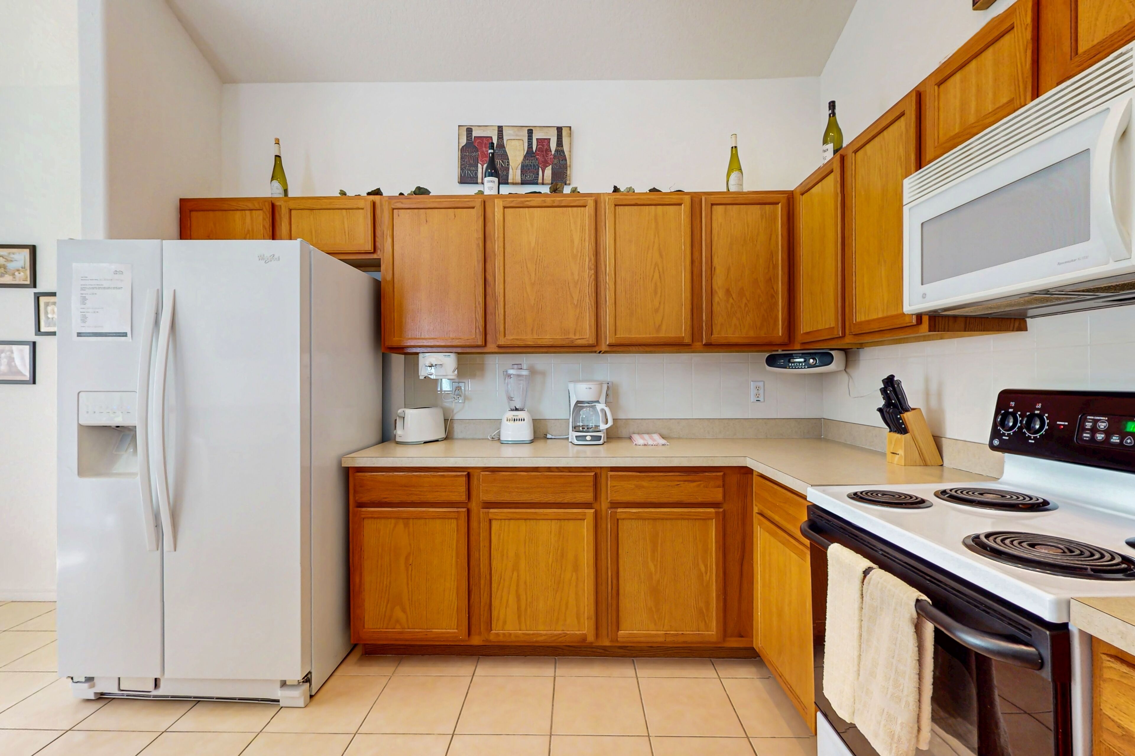 Une cuisine moderne avec des meubles en bois, un réfrigérateur blanc, un four à micro-ondes, une cuisinière et une machine à café.