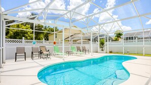 A swimming pool with a white deck, surrounded by lounge chairs and a covered patio area. - Enchanting Dog-friendly Home With Pool, Lanai, Central AC, & Washer/dryer (Kissimmee)