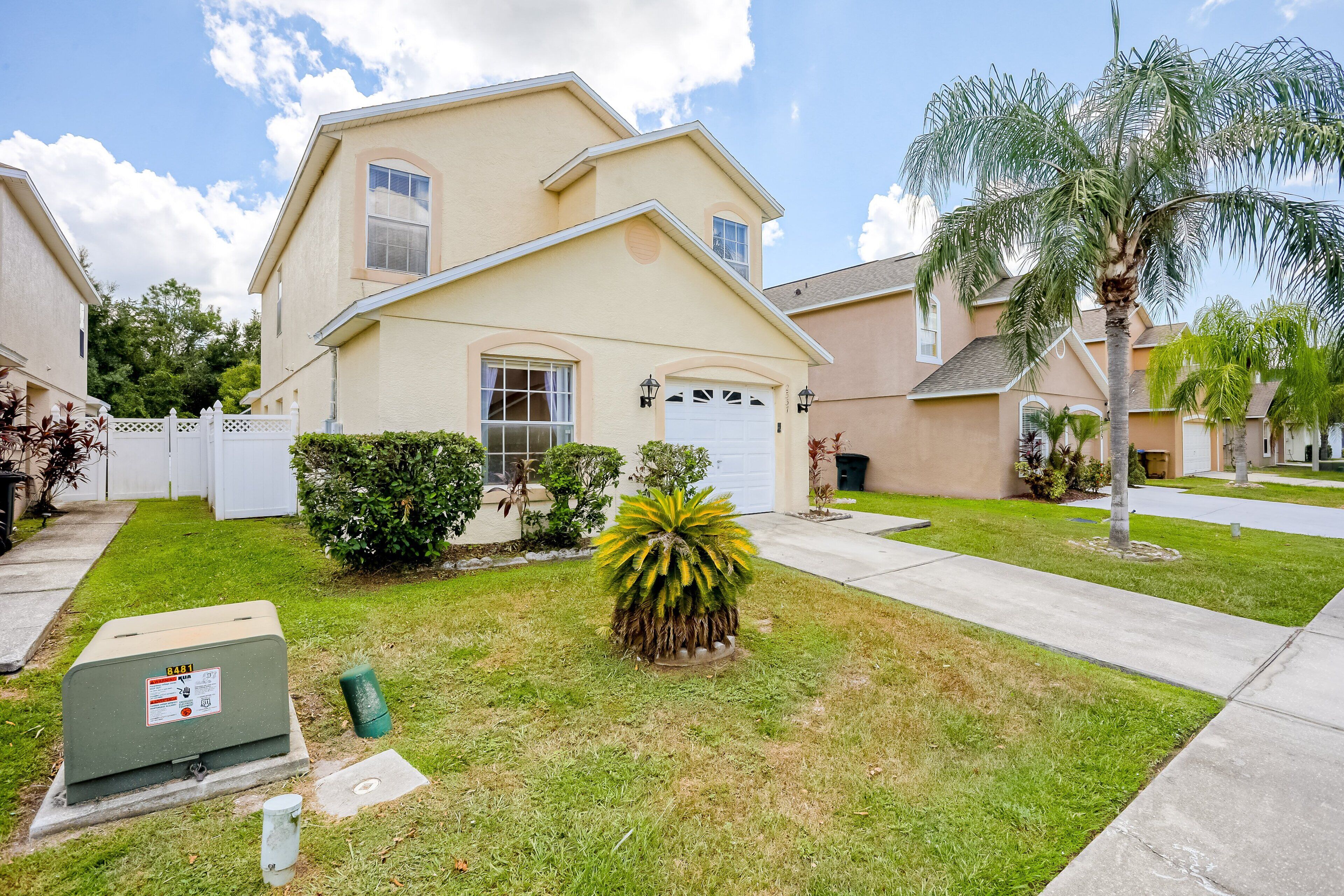 A residential house with a garage, a lawn, and a palm tree.