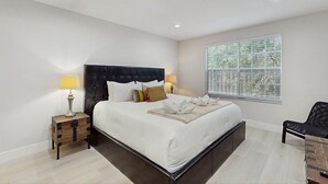 A bedroom with a large bed, bedside lamps, a window with blinds, and a wooden nightstand. - Beautiful Home Boasting Entertainment for Everyone With Wifi (Kissimmee)