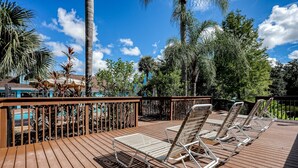 A wooden deck with lounge chairs, a pool, and tropical vegetation. - Beautiful Home Boasting Entertainment for Everyone With Wifi (Kissimmee)
