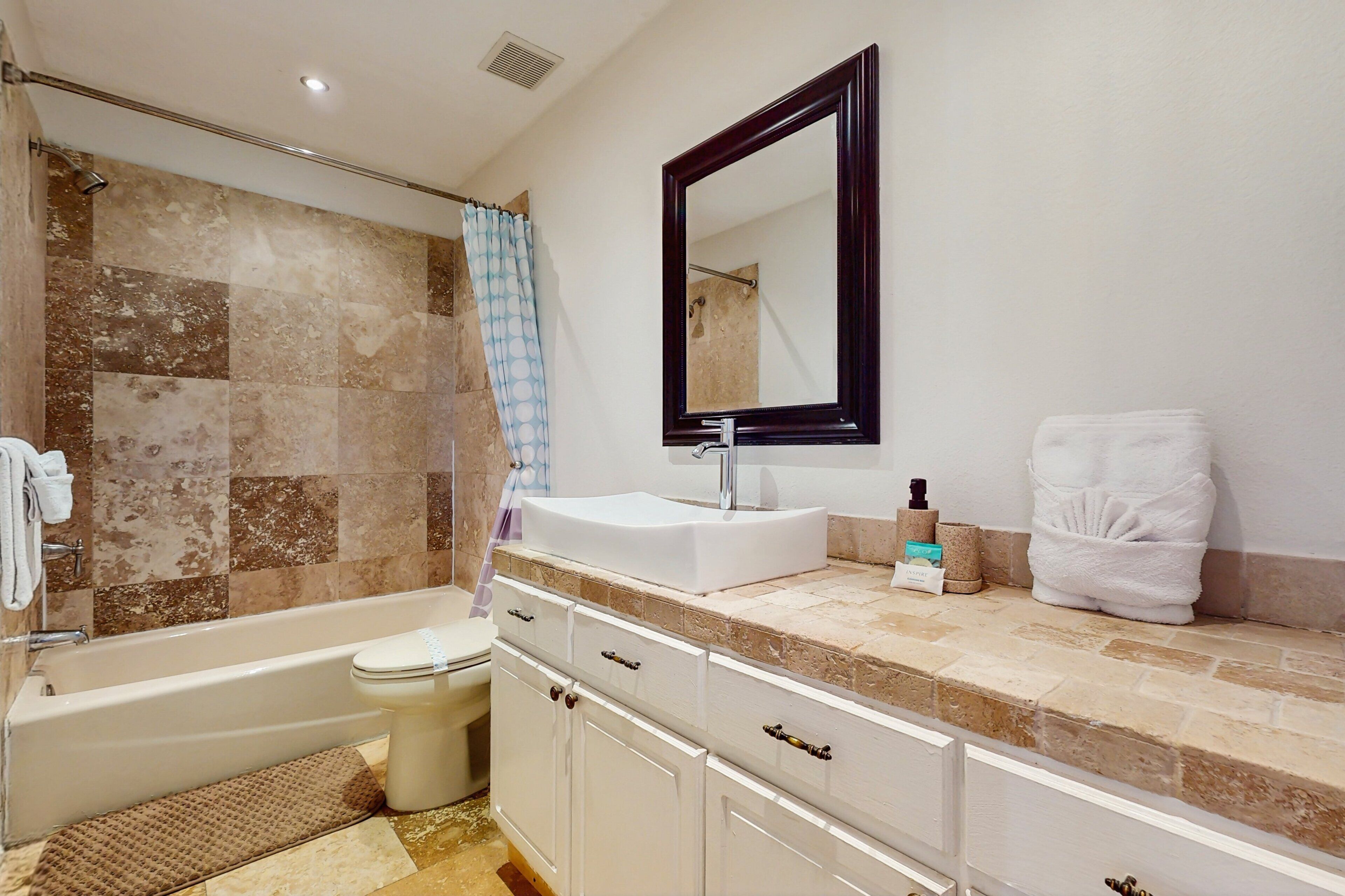 A bathroom with a bathtub, toilet, vanity with a mirror, and a shower area.