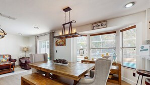 Un espace repas avec une table en bois, des bancs et un luminaire suspendu.