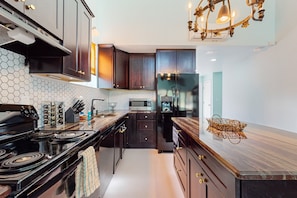 A modern kitchen with dark wood cabinets, a black stove, and a hexagonal tile backsplash.