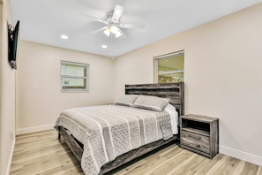 A bedroom with a bed, a nightstand, a ceiling fan, and two windows with blinds. - Dog-friendly Lakefront Home With Fast Wifi, Central AC, Patio, & Game Room (Sebring)