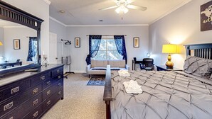 A bedroom with a bed, dresser, mirror, ceiling fan, window with curtains, and a lamp. - Sunny Condo With Pool, hot Tub, Tennis Court, & gym - Balcony & Washer/dryer (Kissimmee)