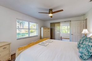 Ein Schlafzimmer mit einem Bett, einem Deckenventilator, einem Kleiderschrank und einer Tür, die nach draußen führt.