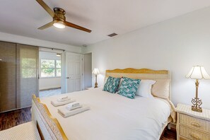 Un dormitorio con cama, lámparas de noche, ventilador de techo y puerta que da a un área exterior.