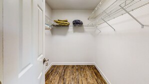 Un armario con estantes metálicos, suelo de madera y una puerta blanca.