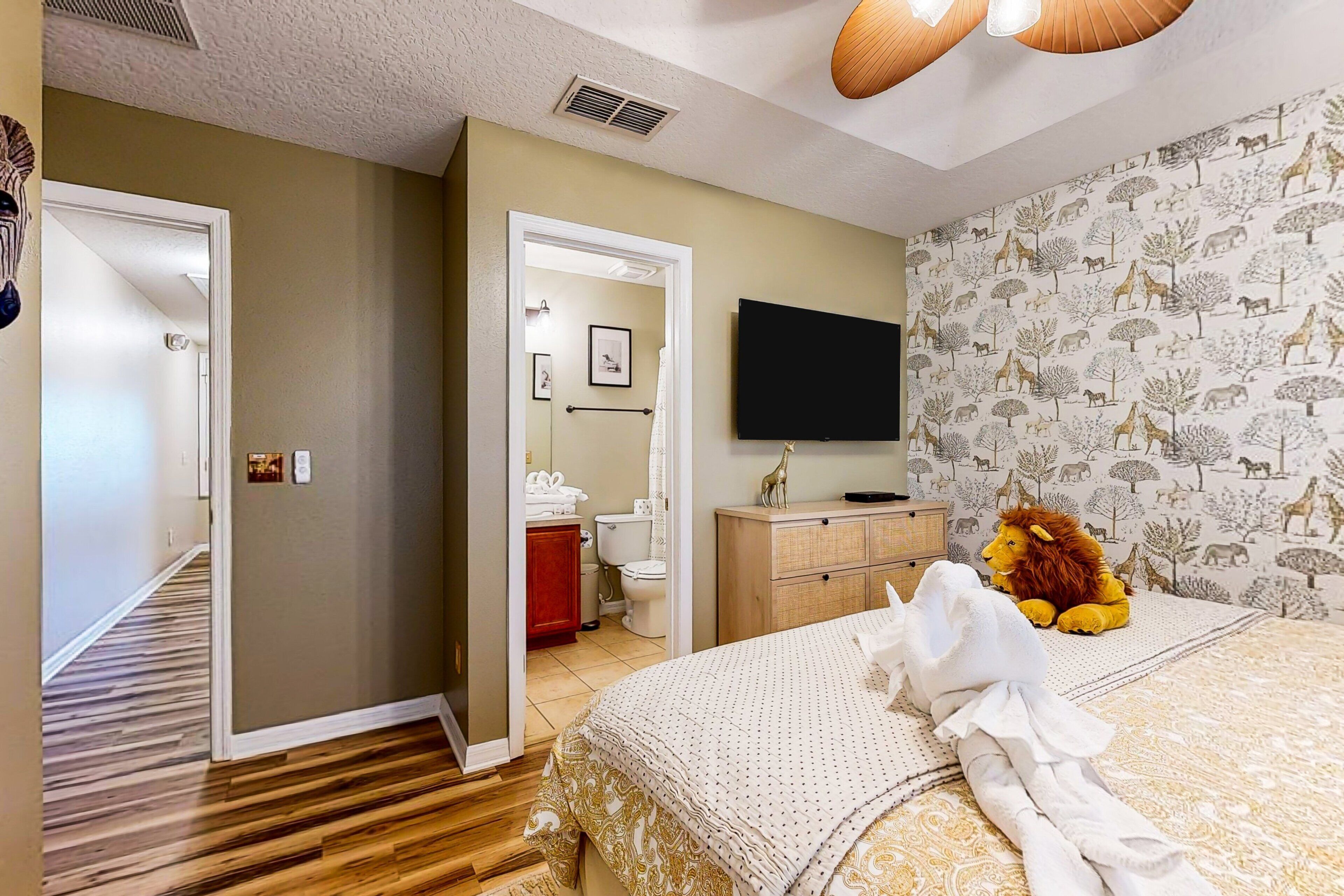 A hotel room with a bed, a television, a bathroom, and a hallway.