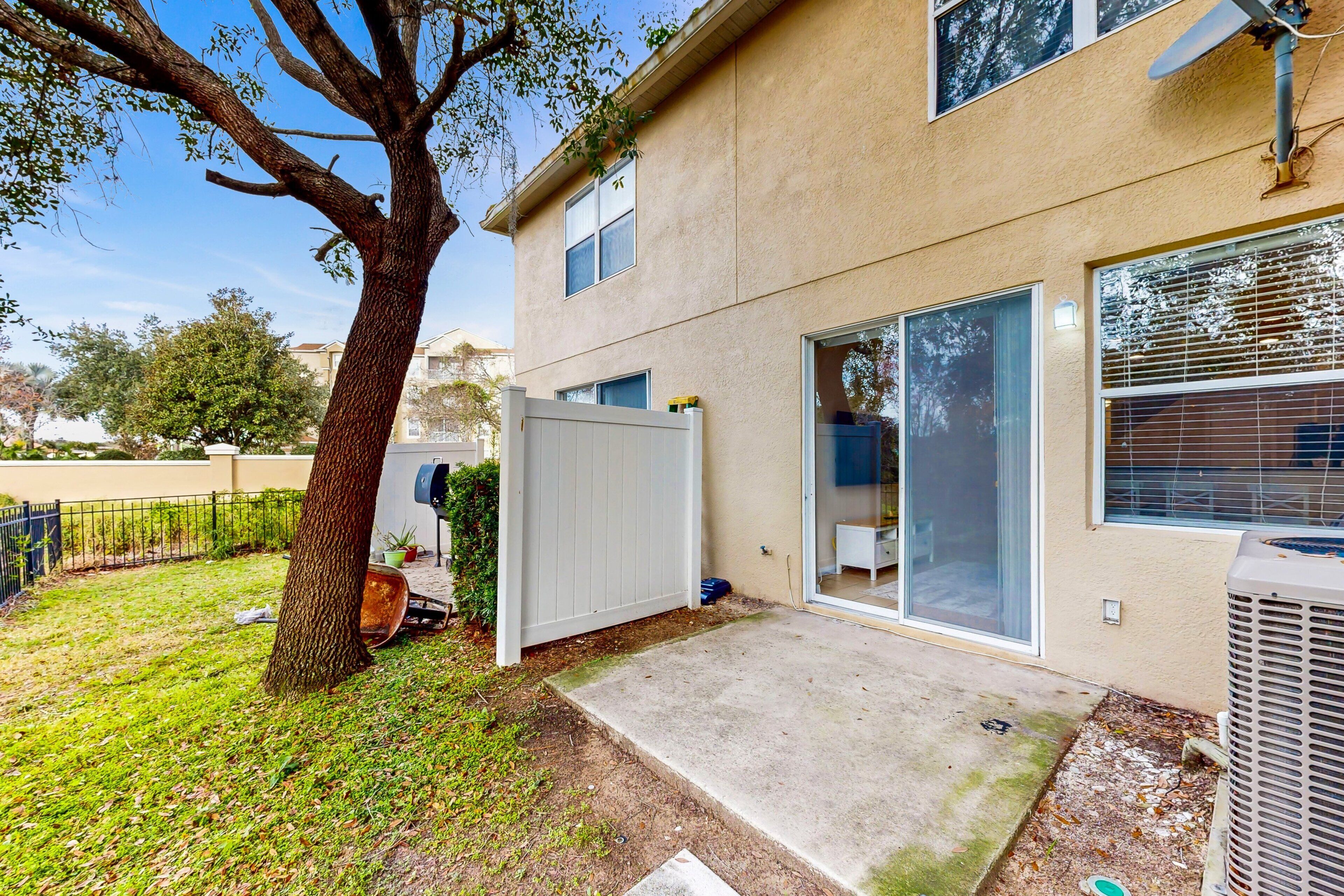 Een woonhuis met een grote boom, een schuifglazen deur en een airconditioning.