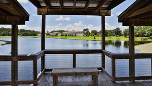 Eine Holzterrasse mit einer Bank, die auf einen ruhigen See und einen Golfplatz im Hintergrund blickt.