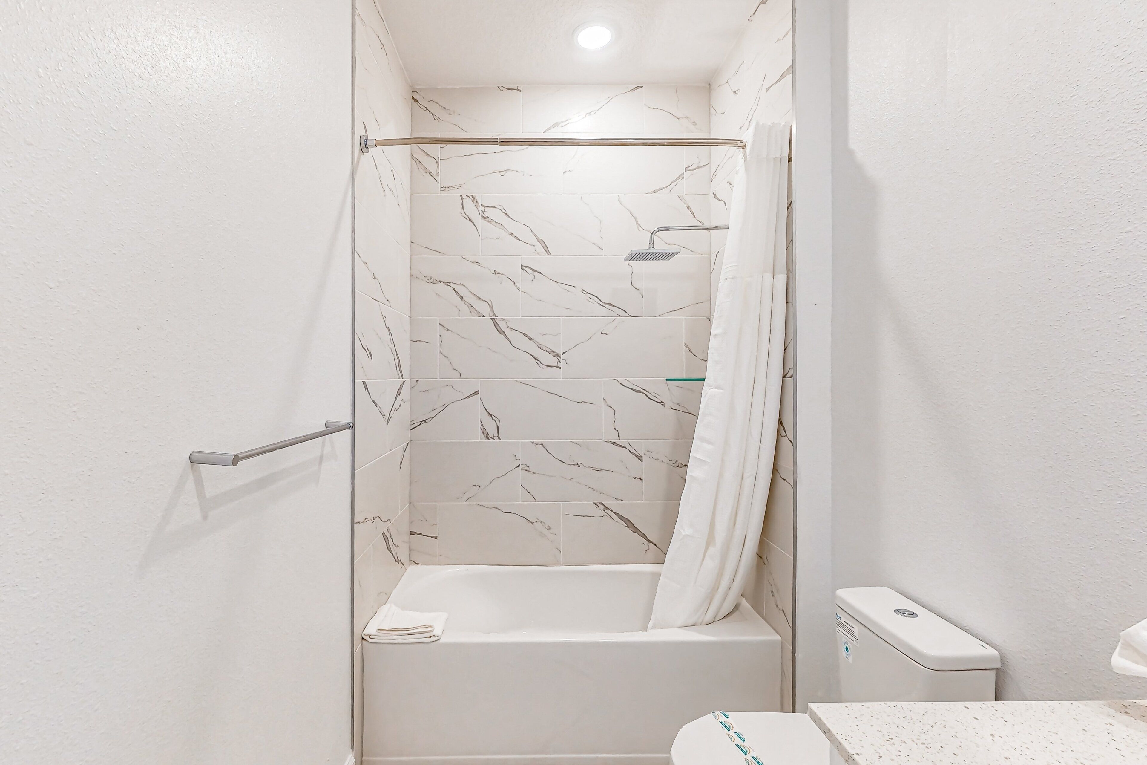 A bathroom with a shower, toilet, and sink.
