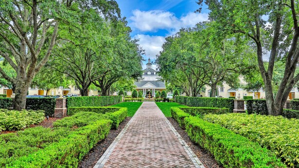 A pathway leading to a building surrounded by trees and hedges. - Golf Course-front Condo With Golf Views, Balcony, Pool, Fast Wifi, Washer/dryer (Kissimmee)