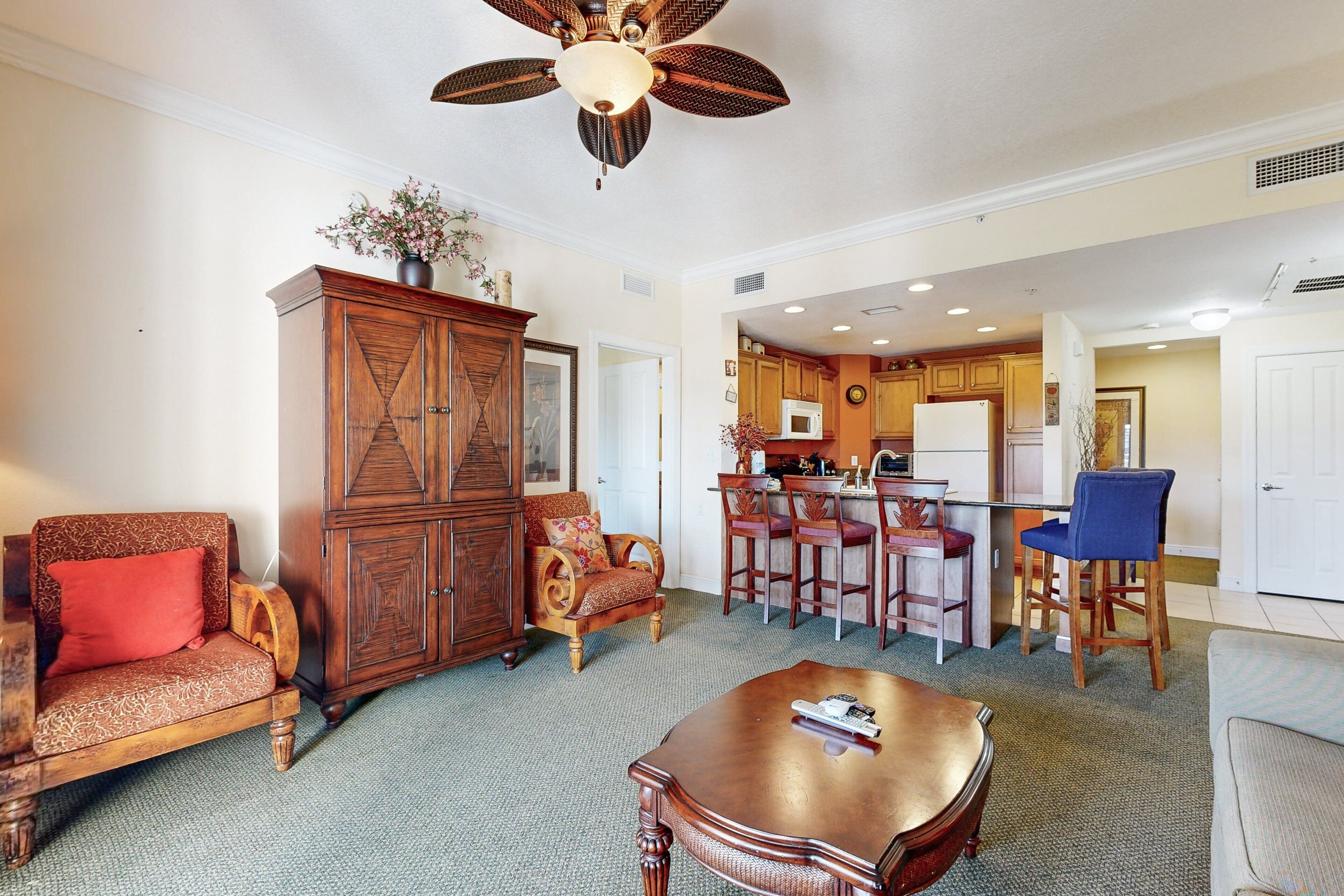 A spacious living room with a wooden cabinet, a sofa, a coffee table, and a ceiling fan.